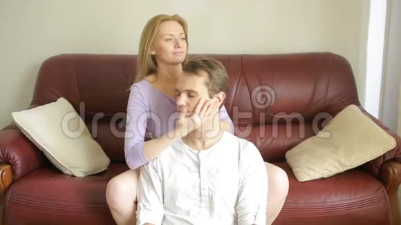 年轻夫妇在客厅的沙发上放松轻轻地拥抱和交谈视频的预览图