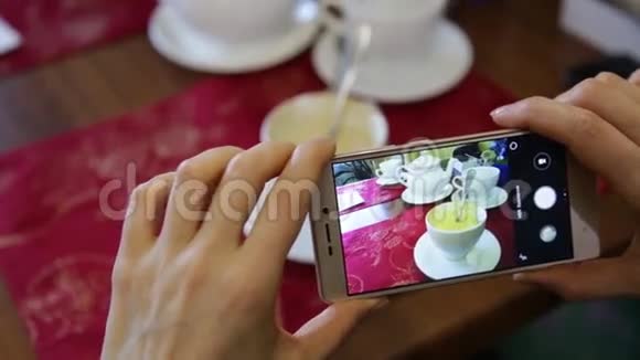 时尚女性在一家餐馆用手机相机为社交网络制作食物照片视频的预览图