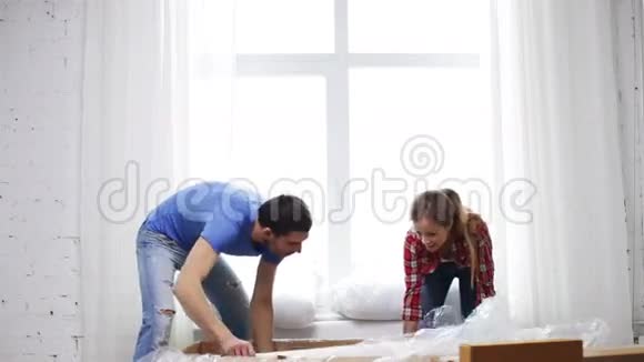微笑的夫妇打开一个大纸板箱和沙发视频的预览图