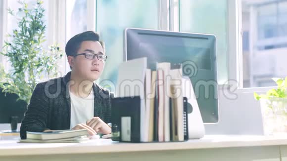 年轻的亚裔男子使用电脑办公视频的预览图