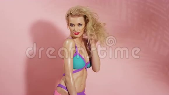 美丽的年轻开朗的女人在粉红色的背景穿着粉红色的背景视频的预览图