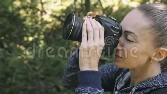 游客在森林中拍摄风景一个高加索女人近距离射击女孩在dslr上拍照视频的预览图