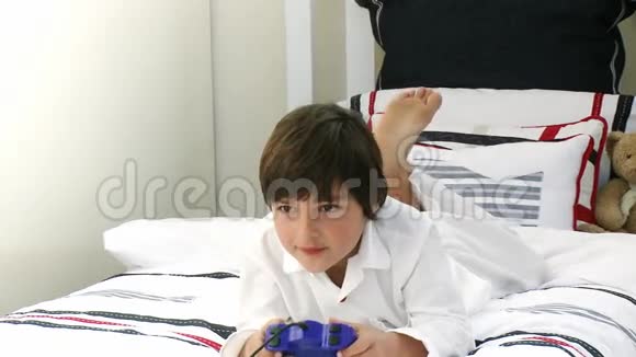 在床上玩电子游戏的男孩视频的预览图