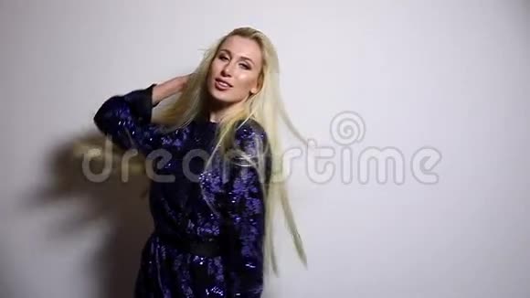 漂亮的金发女人穿着深蓝色长裙在演播室背景下摆姿势慢动作录像视频的预览图