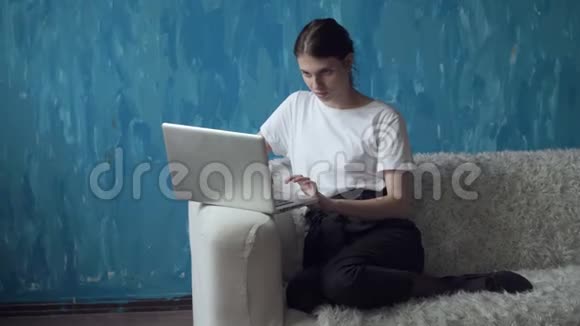 女人在房间里坐在沙发上用笔记本电脑工作视频的预览图