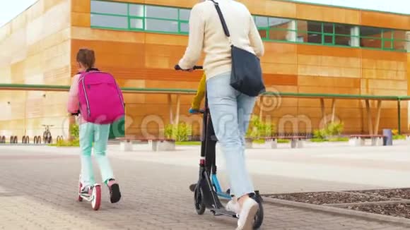 快乐的学童和母亲骑滑板车视频的预览图
