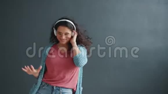 快乐的女学生跳舞享受音乐耳机微笑视频的预览图