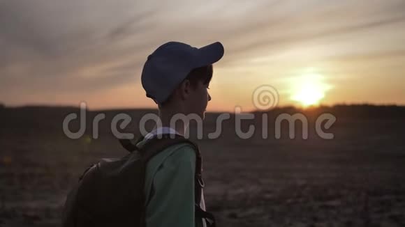 带背包的快乐男孩在日落时在户外散步视频的预览图