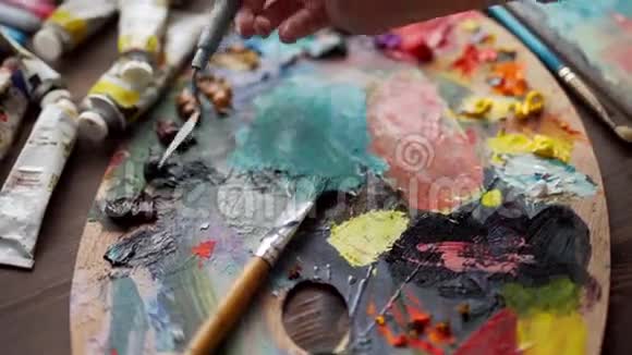 妇女手中的画笔特写将颜料混合在调色板上视频的预览图