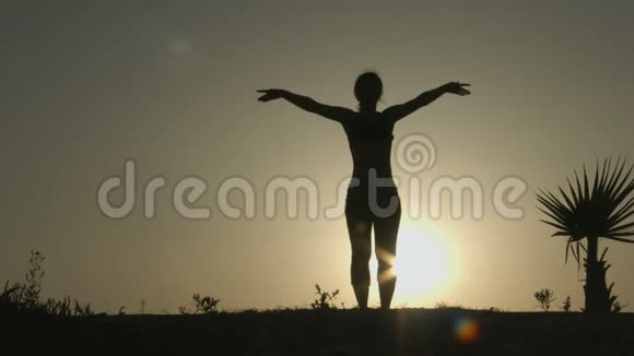 女性在日出光线下练习瑜伽的剪影身心平衡视频的预览图