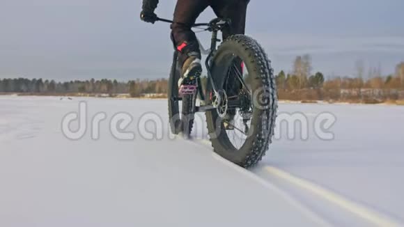 专业的极限运动员骑着一辆肥胖的自行车在户外骑自行车的人在冬天骑在雪冰上男人是视频的预览图