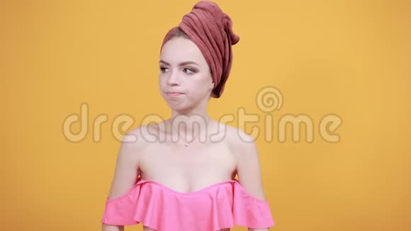 年轻女孩头上的毛巾被隔离的橙色背景显示了情绪视频的预览图