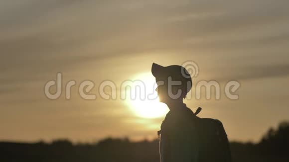 一个带背包的男孩在户外日落时散步的剪影旅行概念视频的预览图