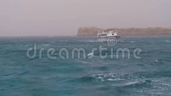 游船与游客在波涛汹涌的海面上的岩石背景下航行埃及视频的预览图
