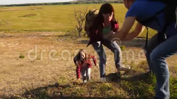 父亲伸出手帮助孩子们爬山一家带着孩子在日落时旅行的游客爸爸视频的预览图
