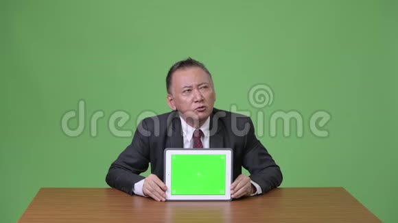 成熟的日本商人展示数字平板电脑视频的预览图