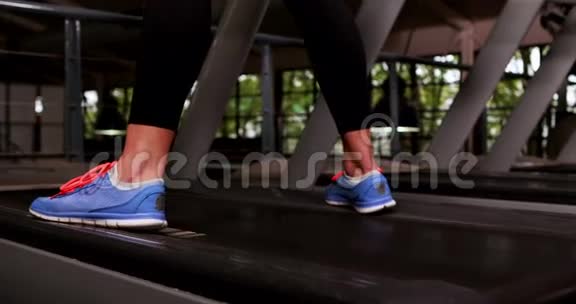 微笑的肌肉女人在跑步机上跑步视频的预览图