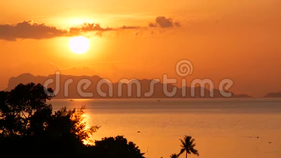 雄伟的热带橙色夏季夕阳在海面上群山的轮廓戏剧性黄昏的空中景色视频的预览图