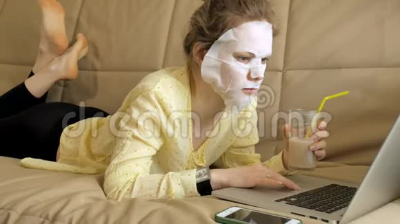 年轻女子带着清洁面罩在家里的笔记本电脑后面工作视频的预览图