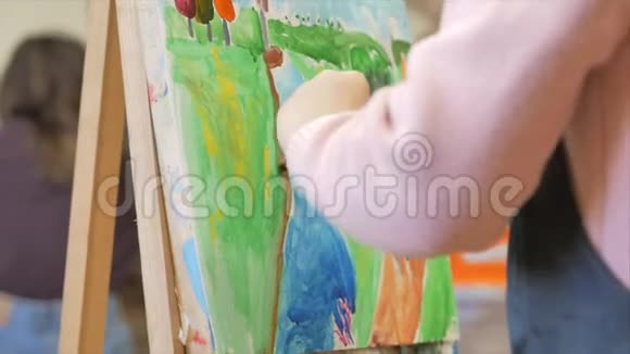 年轻的艺术家小女孩艺术家用画笔画一幅画布坐在桌子上画画布程序视频的预览图