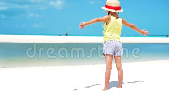 戴帽子的小可爱女孩在白色的热带海滩上下面的动作视频的预览图