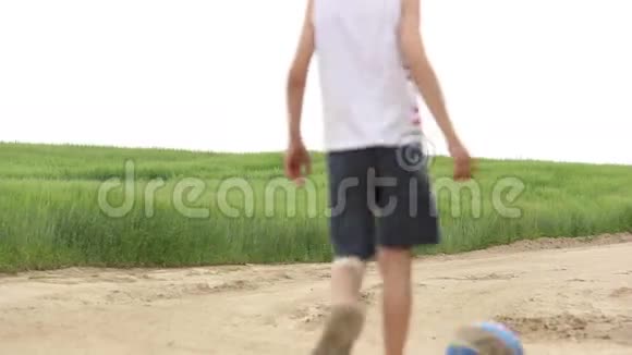 男孩在沙地公路户外踢足球视频的预览图