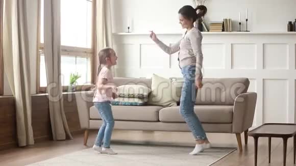 快乐妈妈和可爱的小女孩在客厅跳舞视频的预览图