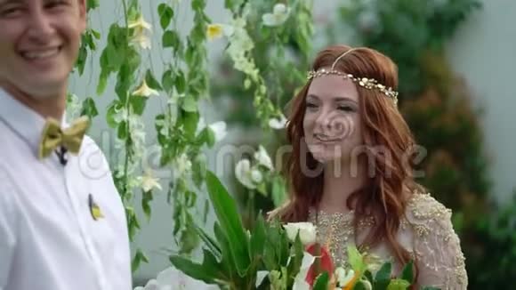 新娘和新郎在婚礼上晚上的热带花园可爱的新婚夫妇视频的预览图