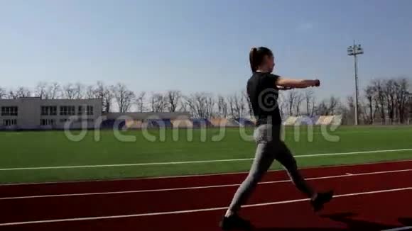 活动健身有吸引力的年轻女孩走路做蹲热身伸展肌肉户外运动在大体育场视频的预览图