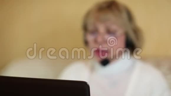 带着耳机的女人在电脑上和顾客交谈视频的预览图