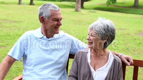 坐在公园长椅上聊天的退休夫妇视频的预览图