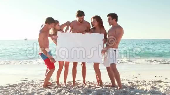 在海滩上拿着空白海报的朋友视频的预览图