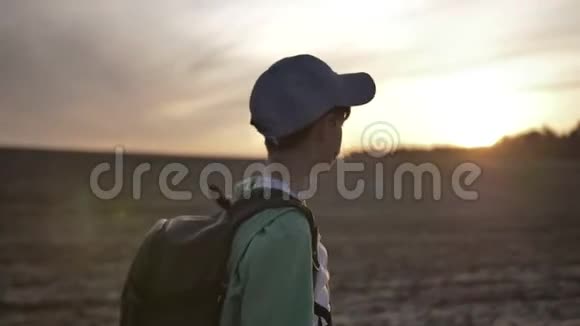 带背包的快乐男孩在日落时在户外散步视频的预览图