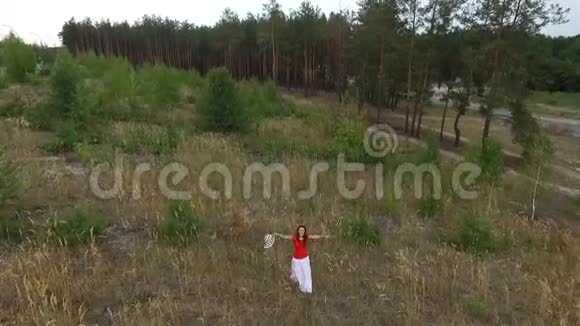 穿着红色衬衫走在田野上的漂亮女人视频的预览图