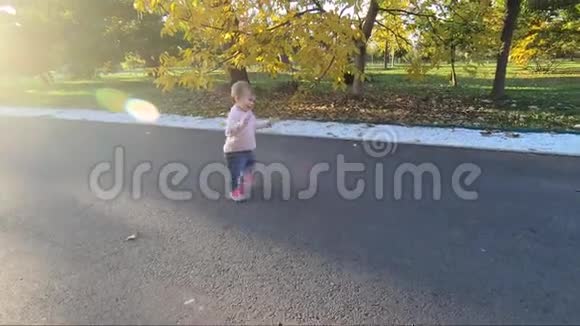 可爱的小女孩在十月在公园散步可爱十个月宝宝走路漂亮快乐的女孩秋天的心情视频的预览图
