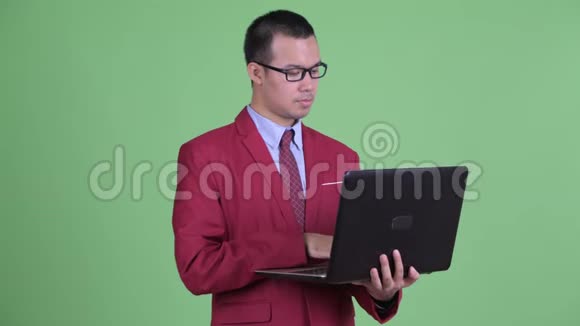 快乐的亚洲商人用笔记本电脑思考视频的预览图