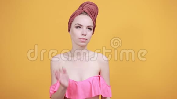 年轻女孩头上的毛巾被隔离的橙色背景显示了情绪视频的预览图