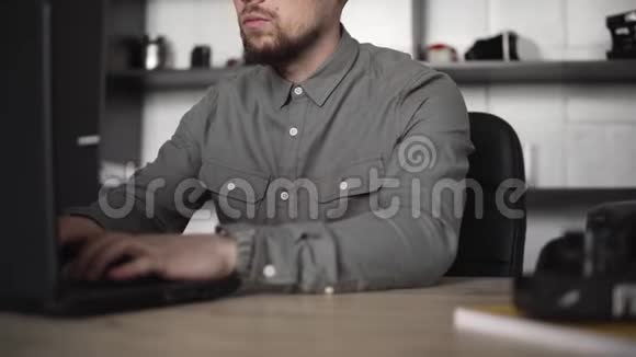 年轻的商人或学生穿着衬衫坐在笔记本电脑上在办公室的一张桌子上用电脑工作视频的预览图