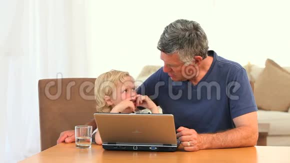 祖父带着孙子看着笔记本电脑视频的预览图