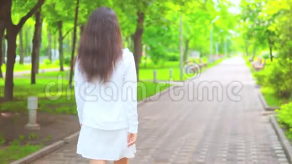 在绿色公园散步的后景妇女视频的预览图