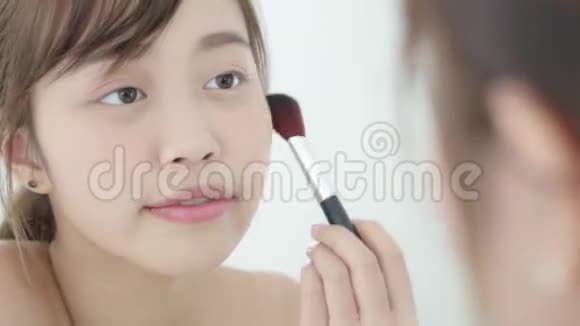 美丽的肖像年轻的亚洲女人微笑着面对镜子在卧室里用刷子涂妆视频的预览图