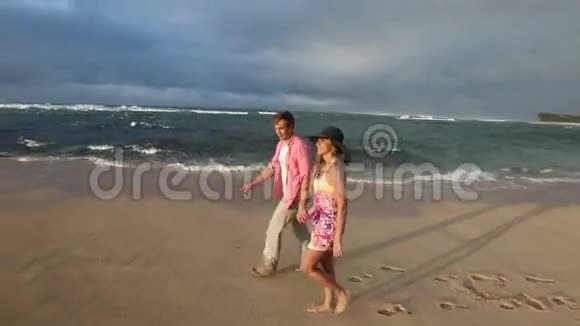 可爱的白种人年轻夫妇牵着手在夏威夷瓦胡岛海滩散步视频的预览图