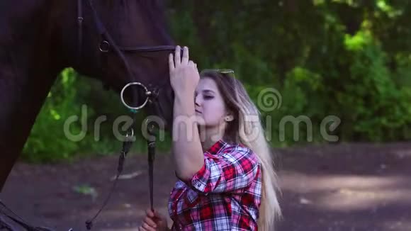 年轻的金发女人穿着格子衬衫和他的马一起散步视频的预览图