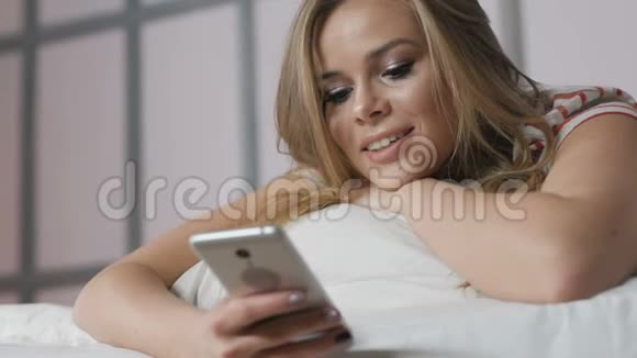 有电话在床上上网的年轻女子视频的预览图