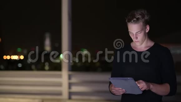 夜间男子户外活动使用数码平板电脑视频的预览图
