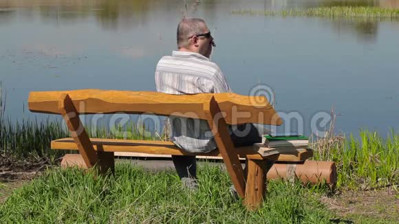 他在河边的长凳上用智能手机说话视频的预览图