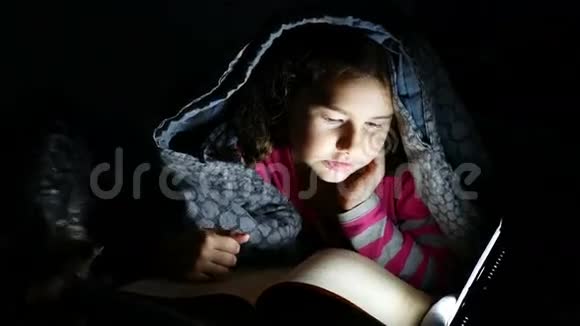 十几岁的孩子在晚上用手电筒在毯子下看书视频的预览图