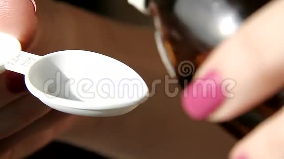 一瓶把止咳糖浆倒入勺子里视频的预览图
