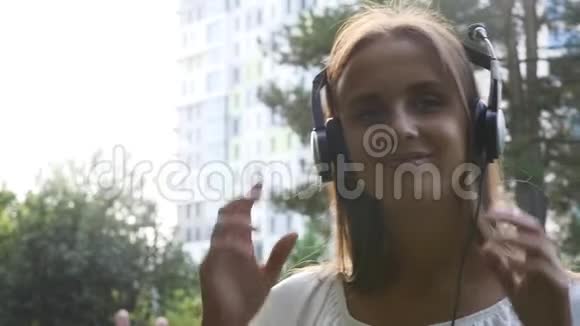 年轻的美女在户外喜欢听耳机音乐视频的预览图