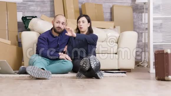 年轻夫妇坐在他们新公寓的地板上视频的预览图